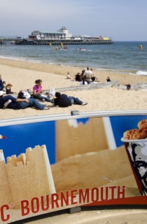 ENGLAND, Dorset, Bournemouth, Tourists playing in the sand and watching speedboat races off the