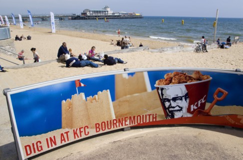 ENGLAND, Dorset, Bournemouth, Tourists playing in the sand and watching speedboat races off the