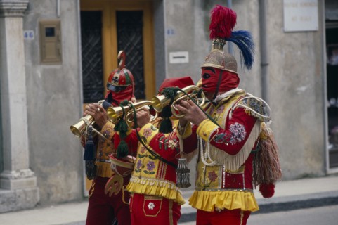 ITALY, Sicily, San Fratello, Bugle players wearing red and yellow costumes and masks celebrating