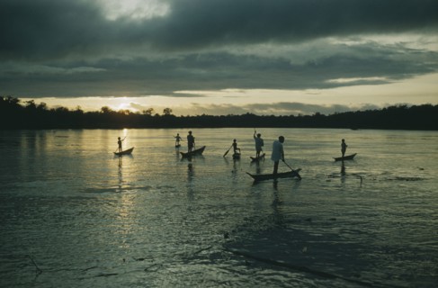 COLOMBIA, Choco Region, Noanama Tribe, Boys paddling canoes on lower rio San Juan at dusk