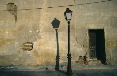 SPAIN, Madrid, Street lamp casting shadow against cracked and peeling plaster wall.