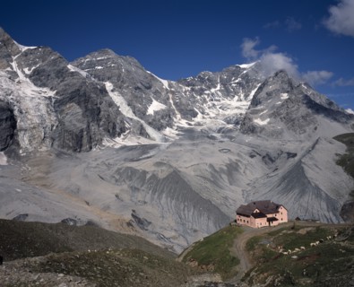 ITALY, Dolomites, Trentino, Sulden. A single pink building at the foot of Schaubachhutte with Mount