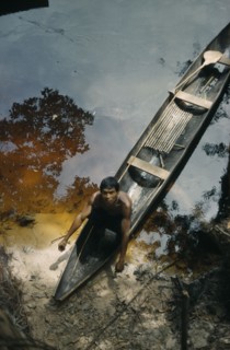 COLOMBIA, Vaupes Region, Tukano Tribe, Man beaches his canoe at a river port; note fishing rod and