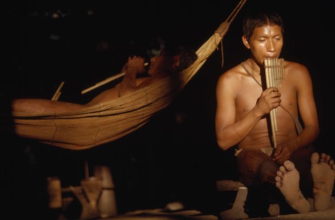 COLOMBIA, Vaupes Region, Tukano Tribe, "Boys playing panpipes at dusk in entrance to maloca /