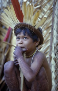 COLOMBIA, Vaupes Region, Tukano Tribe, Young boy playing panpipes outside maloca prior to a