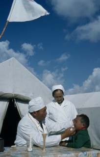 KAZAKHSTAN, Kirgiziya, Mountain doctor and nurse treating young boy.