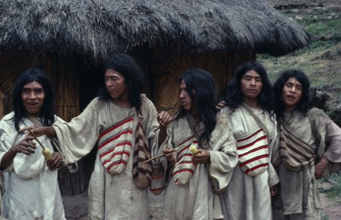 COLOMBIA, Indigenous Tribes, Kogi, Chendukua. A group of Kogi men outside a grass-thatched village