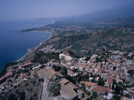 ITALY, Sicily, Messina, View South over the rooftops of  the town of Taormina to Giardini Naxos.