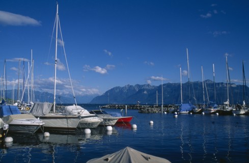 SWITZERLAND, Vaud, Lutry, Boats moored in marina with view across Lake Geneva beyond.