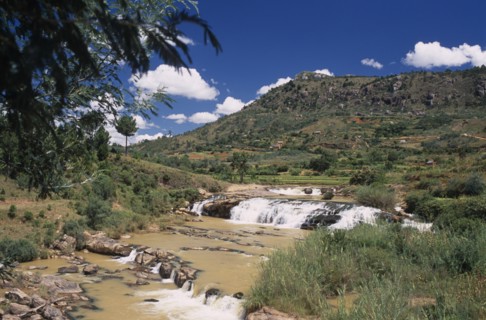 MADAGASCAR, Landscape, Road to Antsirabe. River and waterfall running between green landscape with
