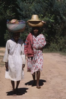 MADAGASCAR, People, Women, Near Ambositra. Two barefooted women walking up a dirt track carrying