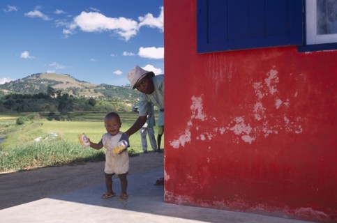 MADAGASCAR, People, Road to Fianarantsoa. Toddler with Grandmother appearing from around exterior