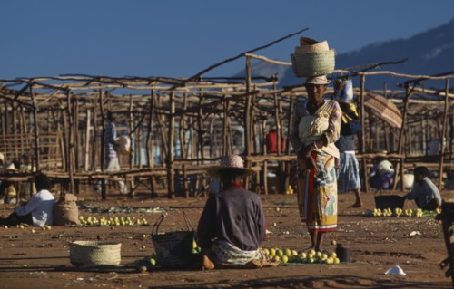 MADAGASCAR, Ambalavao, Two women selling fruit at a sunday market place with empty stalls one woman