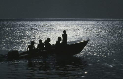JAMAICA, Transport, People traveling on a motorboat at night silhouetted against the light of the