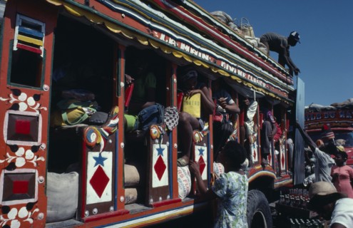 HAITI, Transport, Colourfully painted bus with people loading goods onto the roof