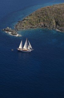 WEST INDIES, US Virgin Islands, St Thomas, Elevated view over sailing boat passing rocky projectory
