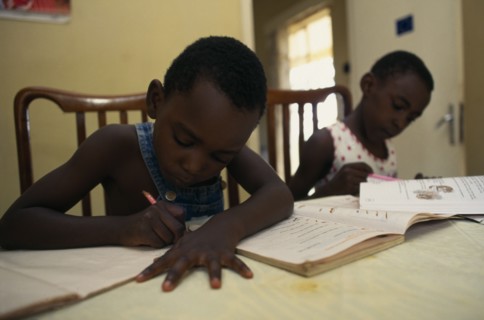 UGANDA, Kampala, Two young children doing homework.