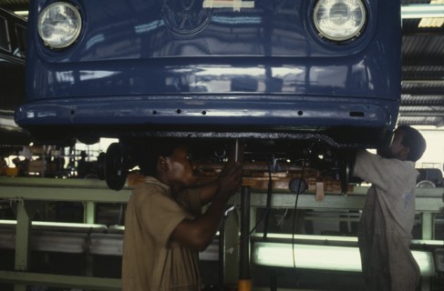NIGERIA, Lagos, Men working on underside of car on Volkswagen car assembly line.