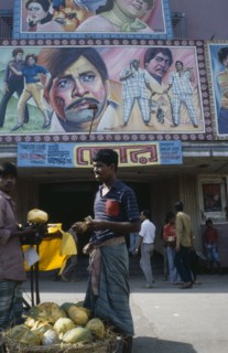 BANGLADESH, Dhaka, Cinema with colourful poster hoadings above entrance and men at a fruit stall in