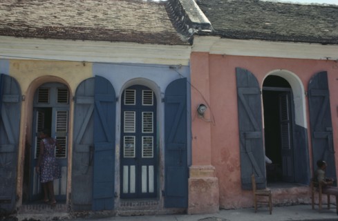 HAITI, Cap Haitien, Street scene with typical colonial style architecture and young woman standing