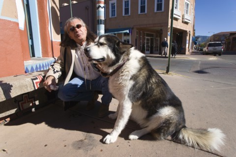 USA, New Mexico, Santa Fe, Native American man feeding his dog outside Father Sky Mother Earth