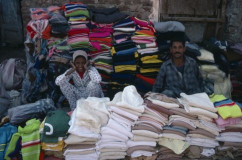 EGYPT, Market, Smiling male and female vendors of pavement stall selling clothing.