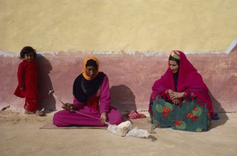 EGYPT, Western Desert, Bedouin, "Women and child in colourful dress spinning wool, sitting against