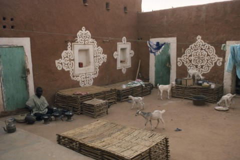 MAURITANIA, Oualata, "Man preparing food in courtyard of buildings with traditional bas-relief