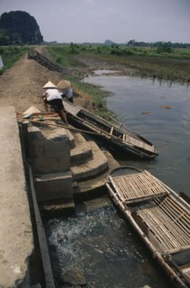 VIETNAM, Hoa Binh Province, Hoa Lu, People moving boat over dyke