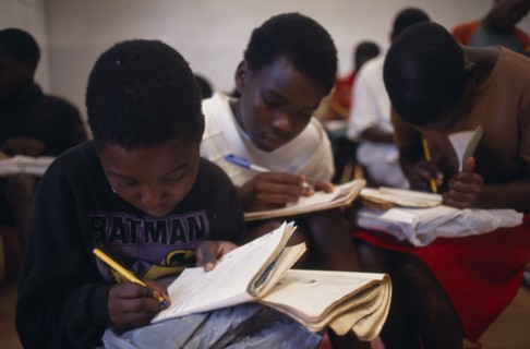 MOZAMBIQUE, Espungabera, Schoolchildren writing in exercise books.