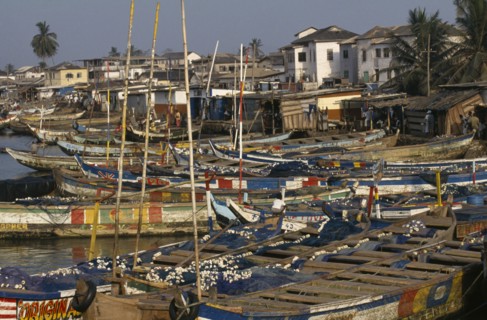 GHANA, Elmina, Moored fishing boats and waterfront buildings.