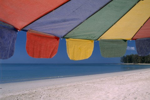 THAILAND, North Phuket, Naiyang Beach, Close up of a multi coloured parasol on the sandy beach.