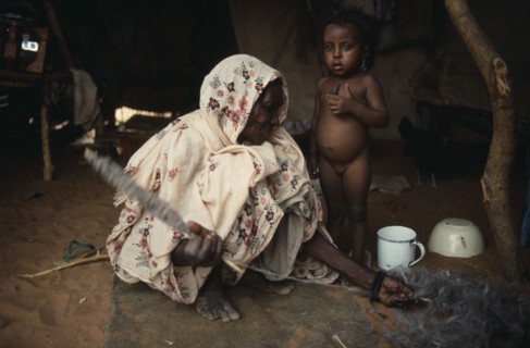 SUDAN, North Kordofan, Work, Kababish nomad woman spinning wool inside hut with little girl