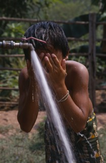 LAOS, Water, Child in Hmong village washing with water from UNHCR supplied tap.
