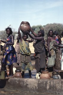 SUDAN, Habila Settlement, Group of Chadian refugee women collecting water from well.
