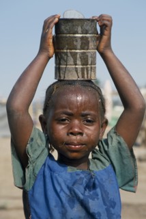 GUINEA, Kissidougou Camp, Portrait of Sierra Leonean refugee girl carrying can of water on her head