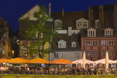 LATVIA, Old Riga, "Rows of floodlit bars, people sat at outside tables with large parasols."