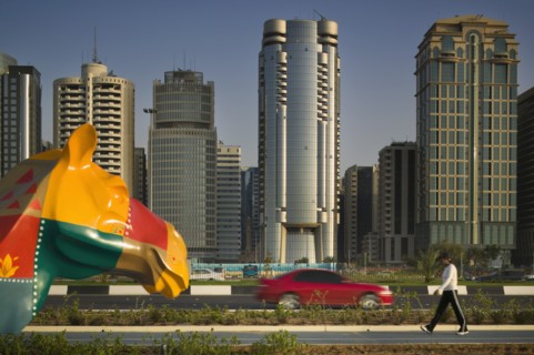 UAE, Abu Dhabi, "City centre skyline along the Corniche. Statue of a colourful patchwork camel, red