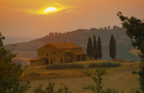 ITALY, Tuscany, Farmhouse and cypress trees at sunset near San Quirico d’Orcia.