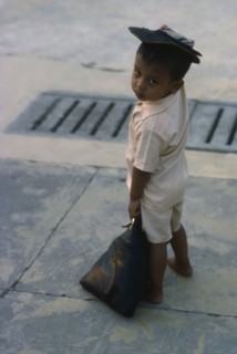 MYANMAR, Yangon, Portrait of young child standing on pavement.