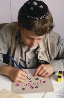 ENGLAND, Religion, Judaism, Boy at Sunday school wearing a kippah and making a card with Hebrew
