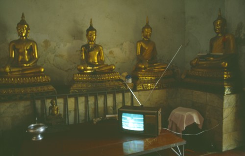 THAILAND, Media, Television, Thai boxing on television inside a monastery in front of seated Buddha