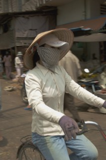 VIETNAM, South, Ho Chi Minh City, Woman wearing a conical hat with a scarfe covering her mouth