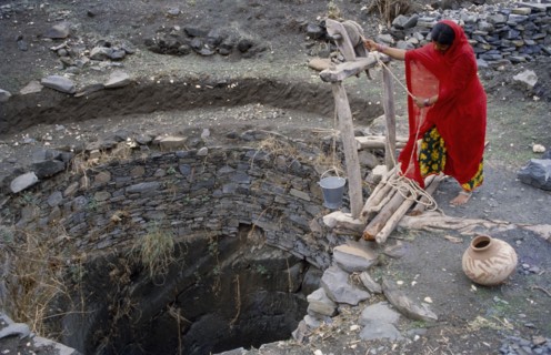 INDIA, Rajasthan, Banswada, Woman collecting water from open well.