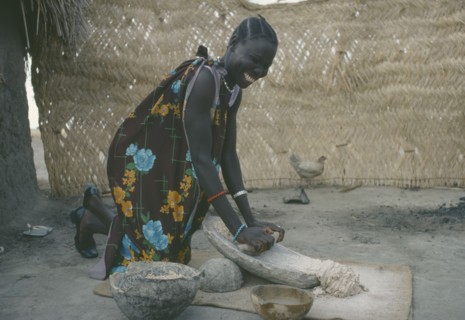 SUDAN, People, Shilluk woman grinding sorghum to make bread.