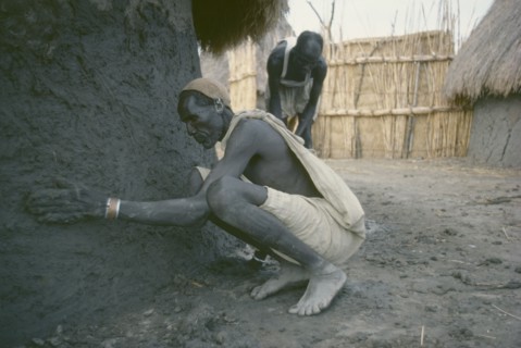 SUDAN, People, Shilluk man plastering exterior wall of mud hut.