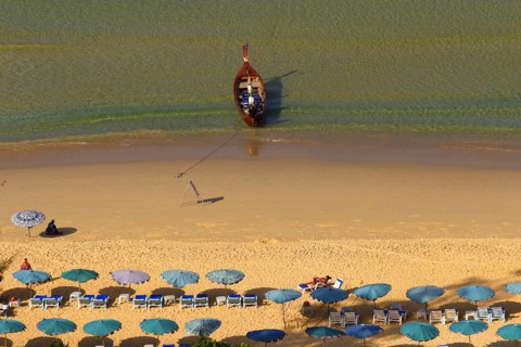 THAILAND, Phuket, Karen Beach, Sun umbrellars on golden sandy beach with boat at shoreline.