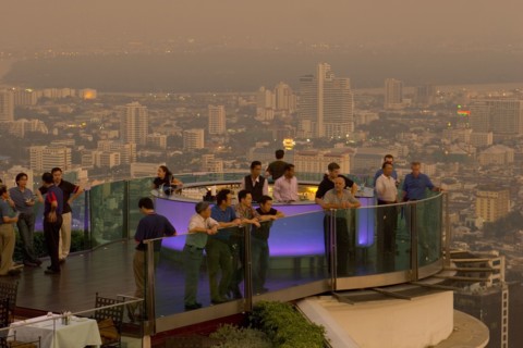 THAILAND, Bangkok, Sorocco Restaurant. People standing next to a lit up bar and looking over