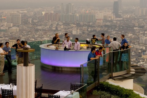 THAILAND, Bangkok, Sorocco Restaurant. People standing next to a lit up bar and looking over