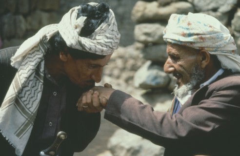 YEMEN, Jebel Aniz, Man kissing the hand of another in traditional Yemen greeting.